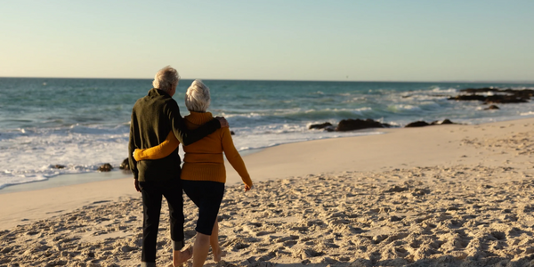 Elderly couple walking on beach.