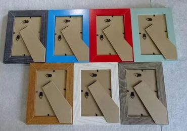 Seven empty photo frames in various colors arranged on a surface.
