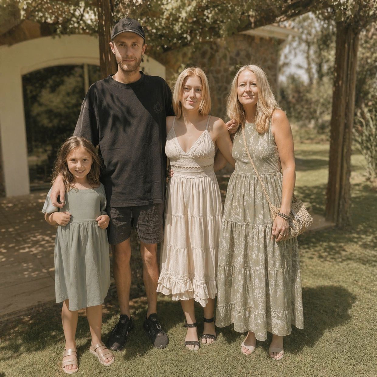 Family of four posing outdoors in summer dresses and casual wear.
