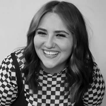 Smiling woman with wavy hair and checkered shirt.