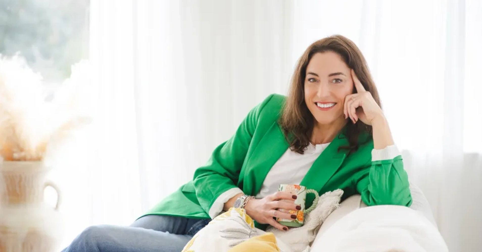 Beth Hammond midlife confidence coach for women sitting on sofa with mug of coffee