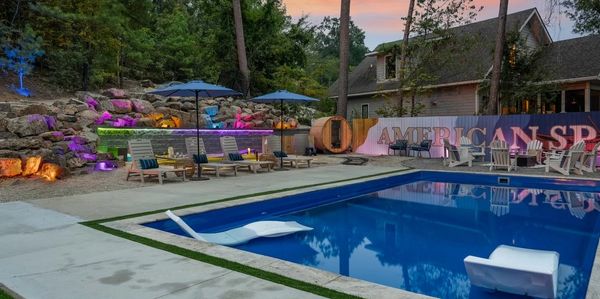 Outdoor pool area with colorful lighting and lounge chairs.