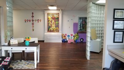 A bright room with wooden floors, a stained glass artwork, and colorful children's toys.