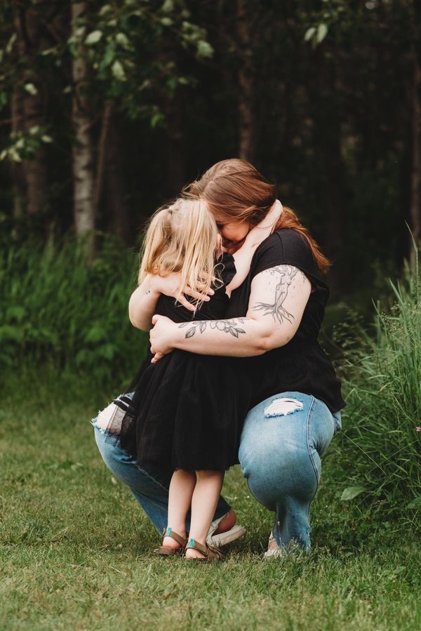 A mother and daughter share a heartfelt embrace outdoors.