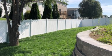 White privacy fence along a lush green lawn.