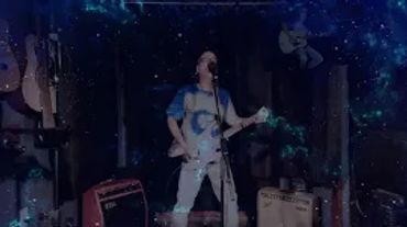Person playing electric guitar on stage with cosmic effects.