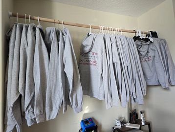 Company hoodies hanging on a pole