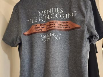 A tshirt hanging on a hangar showcasing a tile company