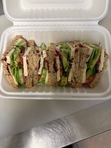 Fresh veggie sandwich with cheese in a white container.