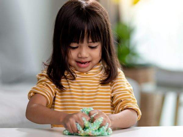 Young female child with sleeves rolled up playing with "slime"