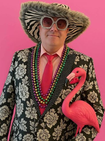 Man in flashy suit and oversized hat with pink flamingo