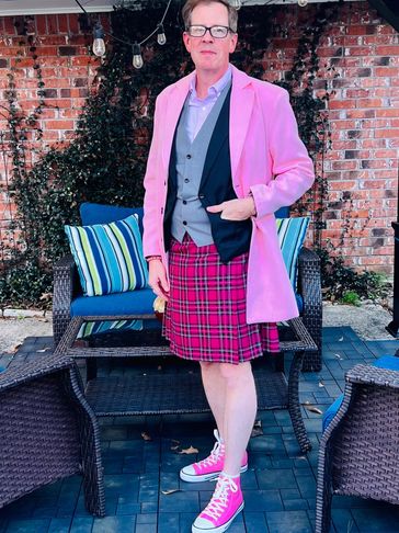 Man wearing a pink jacket and plaid skirt.