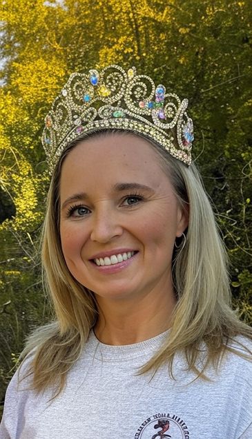 Woman smiling with jeweled crown outdoors.