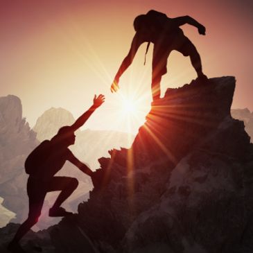 Two climbers helping each other on a mountain at sunset.