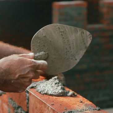 A mason spreading mortar on bricks with a trowel.