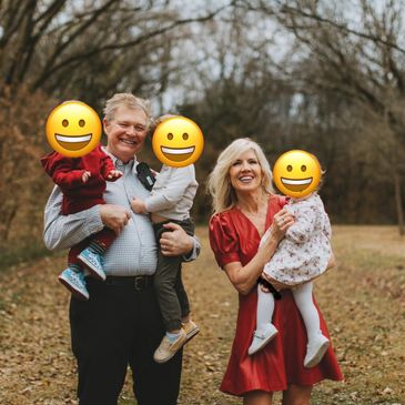 Happy grandparents holding children outdoors in a fall setting.