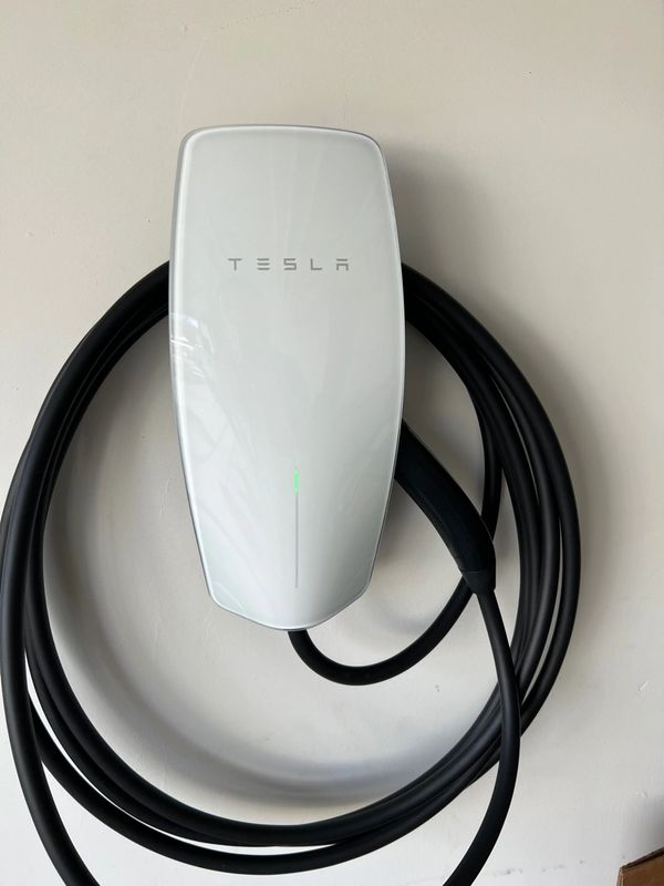 Tesla Wall Connector with the cord wrapped around it and cord end stored in the right side.