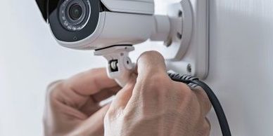 Person installing a security camera on a wall.