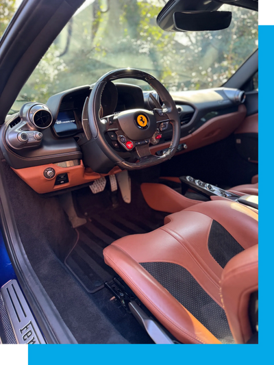 Luxurious Ferrari car interior with leather seats and carbon fiber steering wheel.