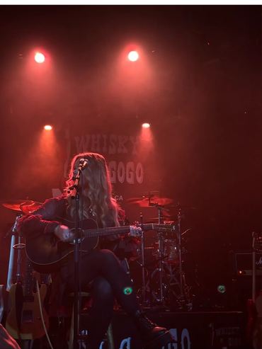 Musician performing with guitar on a dimly lit stage at Whisky a Go Go.