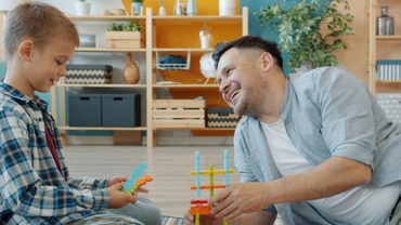 A father playing on the floor with his son