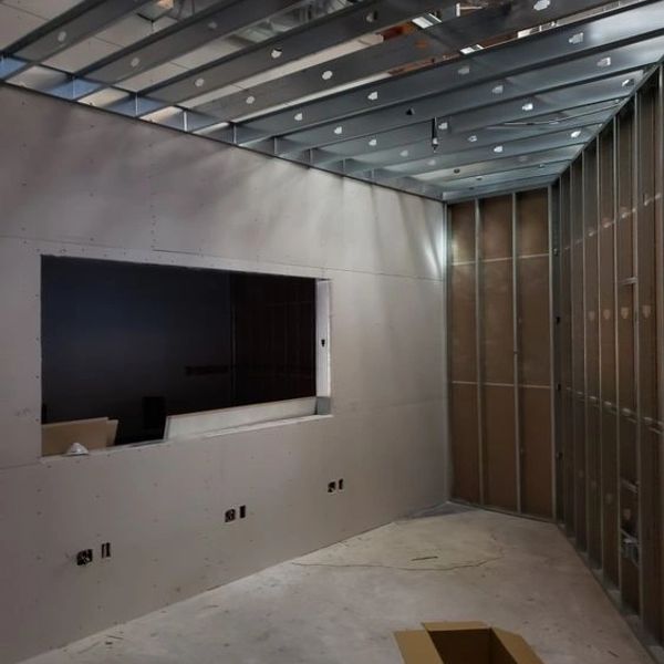 Interior construction site with unfinished drywall and exposed metal framing.