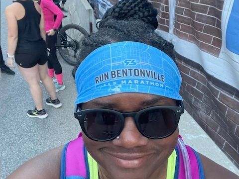 Woman with blue run Bentonville headband with black sunglasses on, nose ring at a race