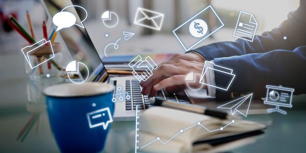 Person typing on laptop with digital business icons overlay.