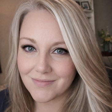 Close-up of a smiling woman with blonde hair and blue eyes.