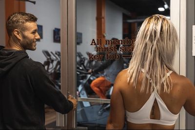 Man opening door for woman entering a gym to workout as a guest or for personal training.