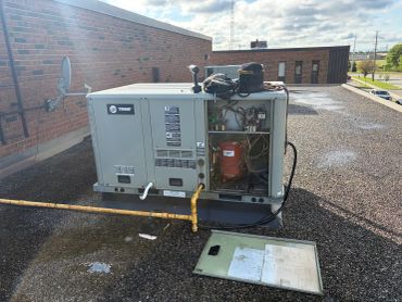 Rooftop HVAC unit with open panel revealing internal components.