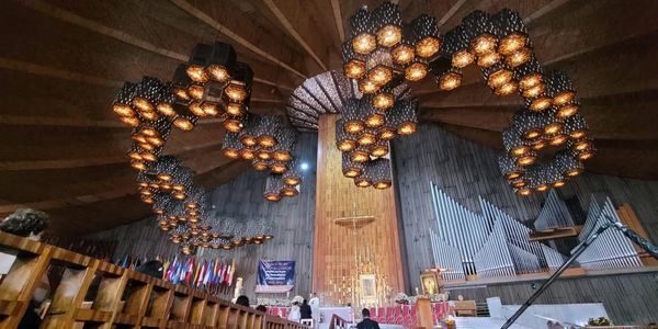 Interior of a church with unique hanging lamps and a wooden ceiling.
