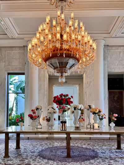 Elegant chandelier above a table with floral arrangements in a luxurious room.