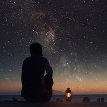 man looking at night sky with later by his side