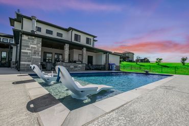 Modern house with a swimming pool and two white pool loungers under a purple sunset sky.