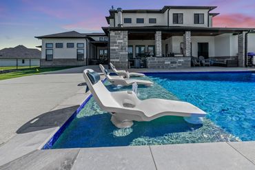 Modern poolside loungers with water jets at a luxurious home during sunset.