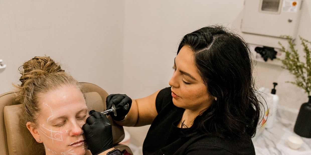 A professional applies cosmetic injections to a client's face in a clinic.