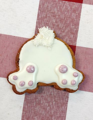 Icing-covered cookie shaped like a bunny's back with paws and tail details.
