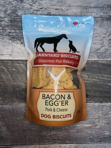 Bag of Barnyard Biscuits Bacon & Egg'er dog treats on wooden surface.