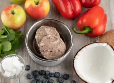 Fresh fruits, vegetables, and a bowl with patties on a wooden surface.