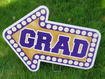 Yard sign: gold arrow with purple border and a purple text inside "GRAD"