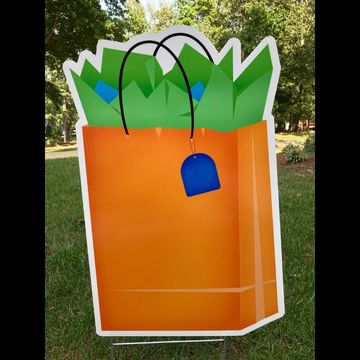 Yard sign: orange gift bag blue tag and green paper inside birthday yard card rental Apex NC