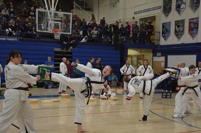 Taekwondo black belts breaking boards for martial arts training.