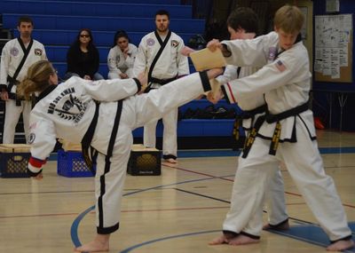 Karate black belt breaking a wooden board with a martial arts kick.