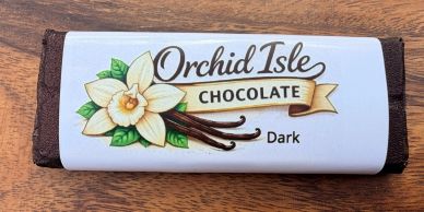 Dark chocolate bar labeled Orchid Isle with vanilla and cocoa pod illustration.