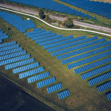 Aerial view of a large solar farm with rows of blue solar panels.