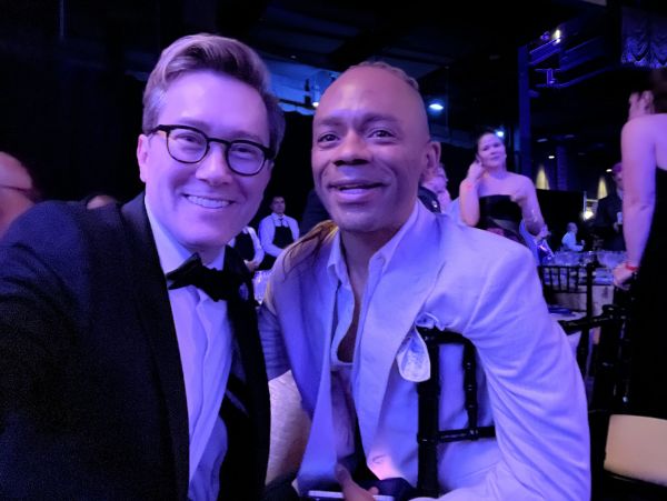 Two men smiling at a formal event with blue lighting.