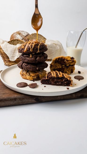 Stack of chocolate cookies drizzled with caramel sauce and served with milk.
