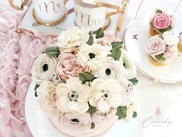 Elegant floral cake with delicate pastel flowers and matching cupcakes.