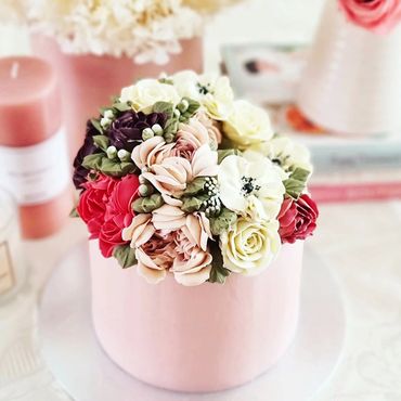 Elegant pink cake adorned with intricate buttercream flowers.